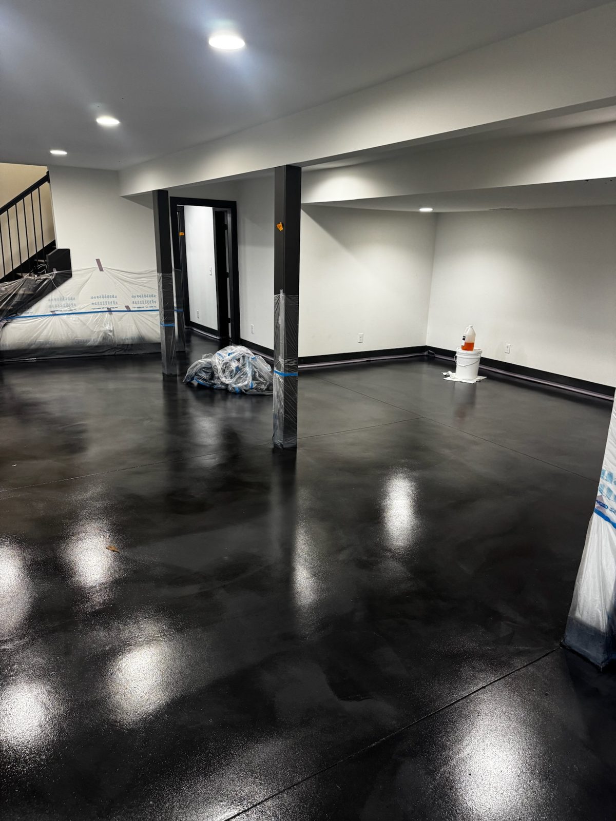 Aria sprayed microcement basement floor with custom stain — Forest Hills, 650 sq ft